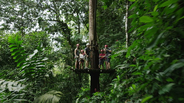 Wide high angle tracking shot of zipline in rain forest trees / Quepos, Puntarenas, Costa Rica