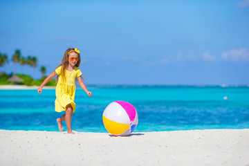 Little adorable girl playing on beach with ball