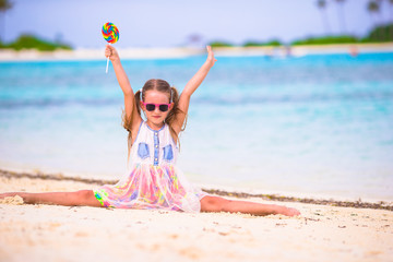 Adorable girl have fun with lollipop on the beach