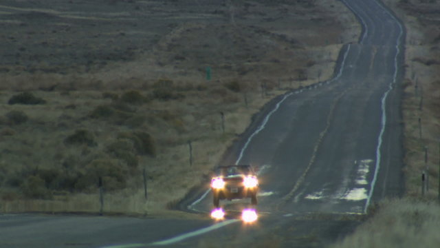vintage red convertible driving at dusk