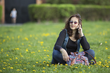 Woman sitting on the grass speaks on his mobile phone.