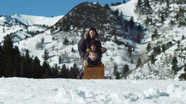 family falling off of a toboggan while sledding