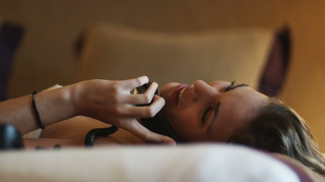 woman lying on a bed talking on the phone 