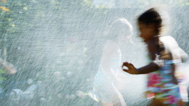 children running in a sprinkler