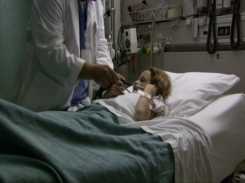 Doctor Explaining Stethoscope To Child In Hospital Bed