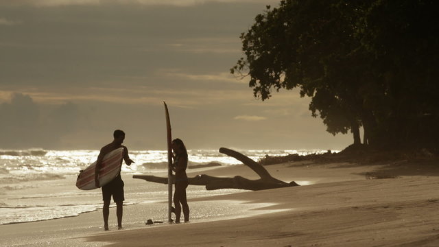 Wide shot of surfers talking on beach / Esterillos, Puntarenas, Costa Rica