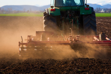 Obraz premium Tractor in sunset plowing the field
