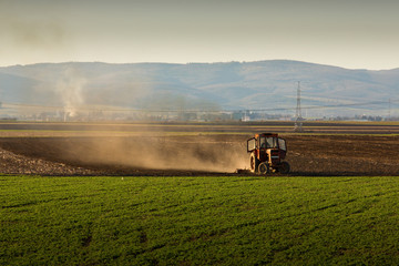 Fototapeta premium Tractor in sunset plowing the field