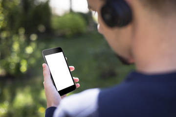 Man holding smartphone and listening to music with wireless headphones