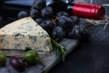 Marble board with cheese selection, wine and grapes