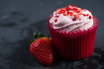 Strawberry cupkace decorated with icing on dark background