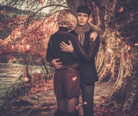 Naklejka premium Elegant couple embracing near river in autumnal landscape