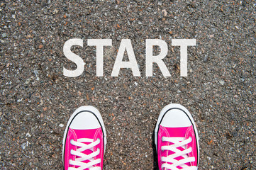 Feet concept with pink sneakers on black background with start t