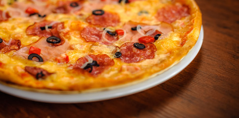 Tasty pizza on a white plate presented on a wooden table