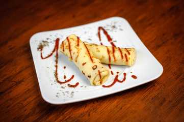 Delicious pancakes with meat, spices and sauce on a white plate