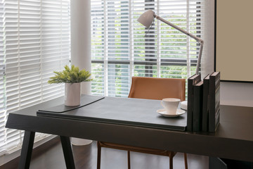 wooden table with lamp and books in modern working room interior
