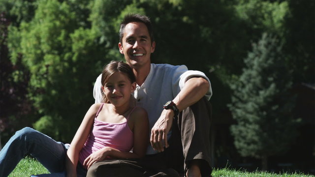 father and daughter sitting together on the grass