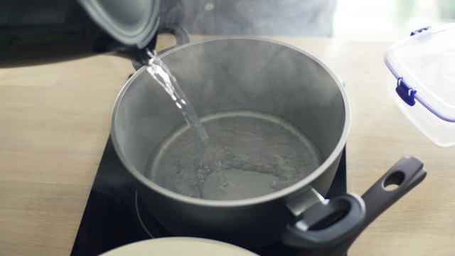 Pouring boiling water from kettle into pot in kitchen,  240fps
