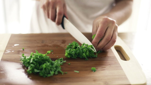 Woman slicing basil in kitchen, slow motion shot at 240fps
