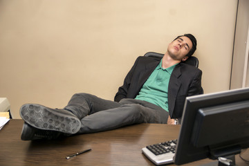 Overworked, tired young businessman sleeping at his desk