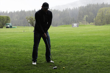 Golfer beim Abschlag im Regen