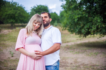 Fototapeta premium man and pregnant woman in nature, amid the pine forest