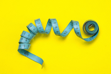 twisted tape measure on yellow background