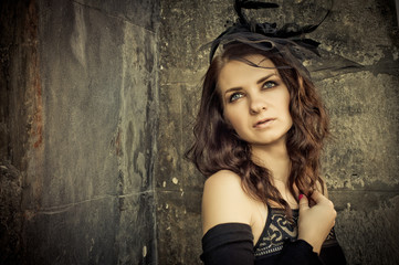 Fototapeta premium Beautiful young brunette woman in a vintage style in evening bla