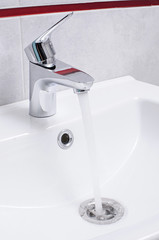 wash basin and running water from the tap in chrome bathroom