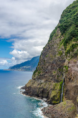 Fototapeta na wymiar Steep northern shore of the island of Madeira, a waterfall.
