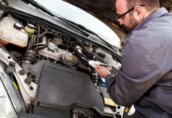Fototapeta na wymiar Auto mechanic checks the oil on a car being repaired