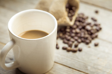 Coffee cup and coffee beans on old wooden background