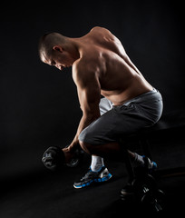 Man with bare chest lifting dumbbells isolated black background.