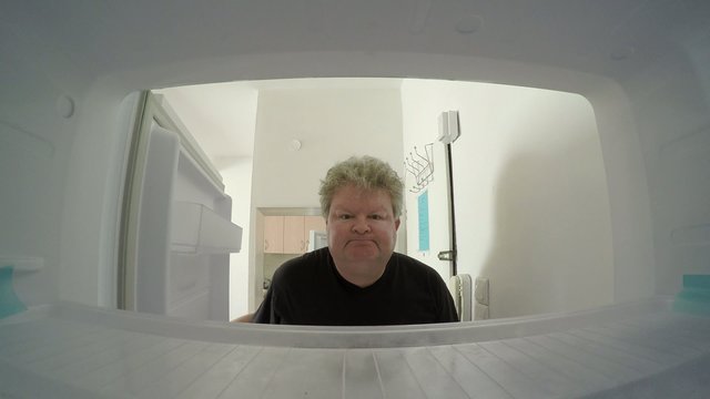 A sad man in diet looks inside empty freezer finds nothing