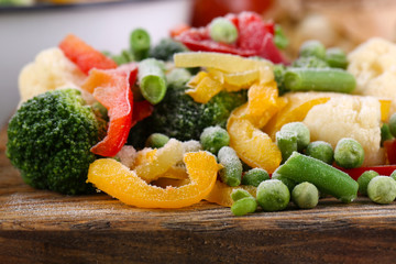 Frozen vegetables on cutting board, on napkin, on wooden table background