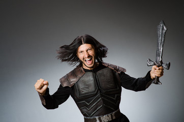 Angry knight with sword against dark background