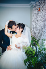 Charming bride with groom embraces and kisses on their wedding