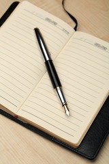 Writing pen and notebook on wooden table, closeup
