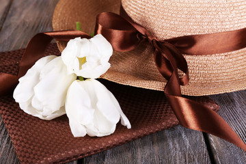 Hat with flowers on wooden background, closeup