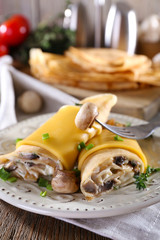 Pancakes with creamy mushrooms in plate on wooden table, closeup