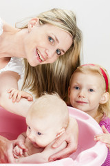 portrait of mother with her baby and daughter during bathing