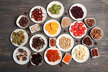 Different products on saucers on wooden table, top view