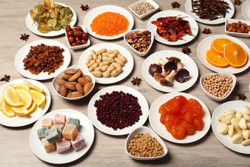 Different products on saucers on wooden table, top view
