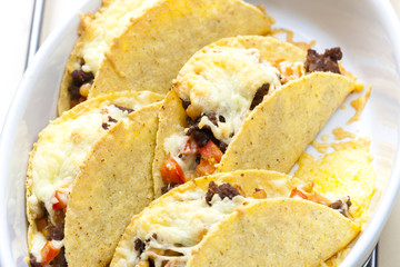 baked tacos filled with minced beef meat, beans and tomatoes