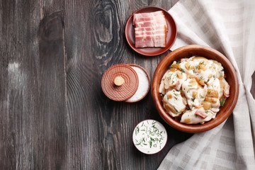 Obraz na płótnie Canvas Fried dumplings with onion and bacon in frying pan, on wooden table background