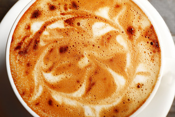 Cup of coffee latte art with grains on wooden table, closeup