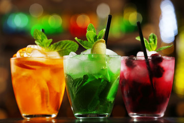 Glasses of cocktails on bar background