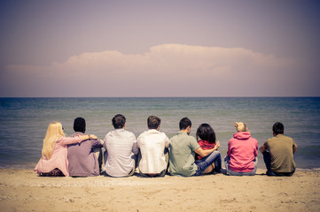 Group of mutiracial friends sitting on the beach 