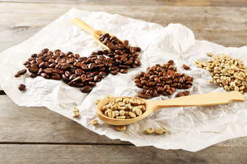 Coffee beans on crumpled parchment on wooden table, closeup