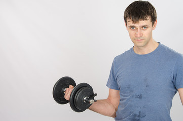 Athlete pumps muscle of the right hand using dumbbells